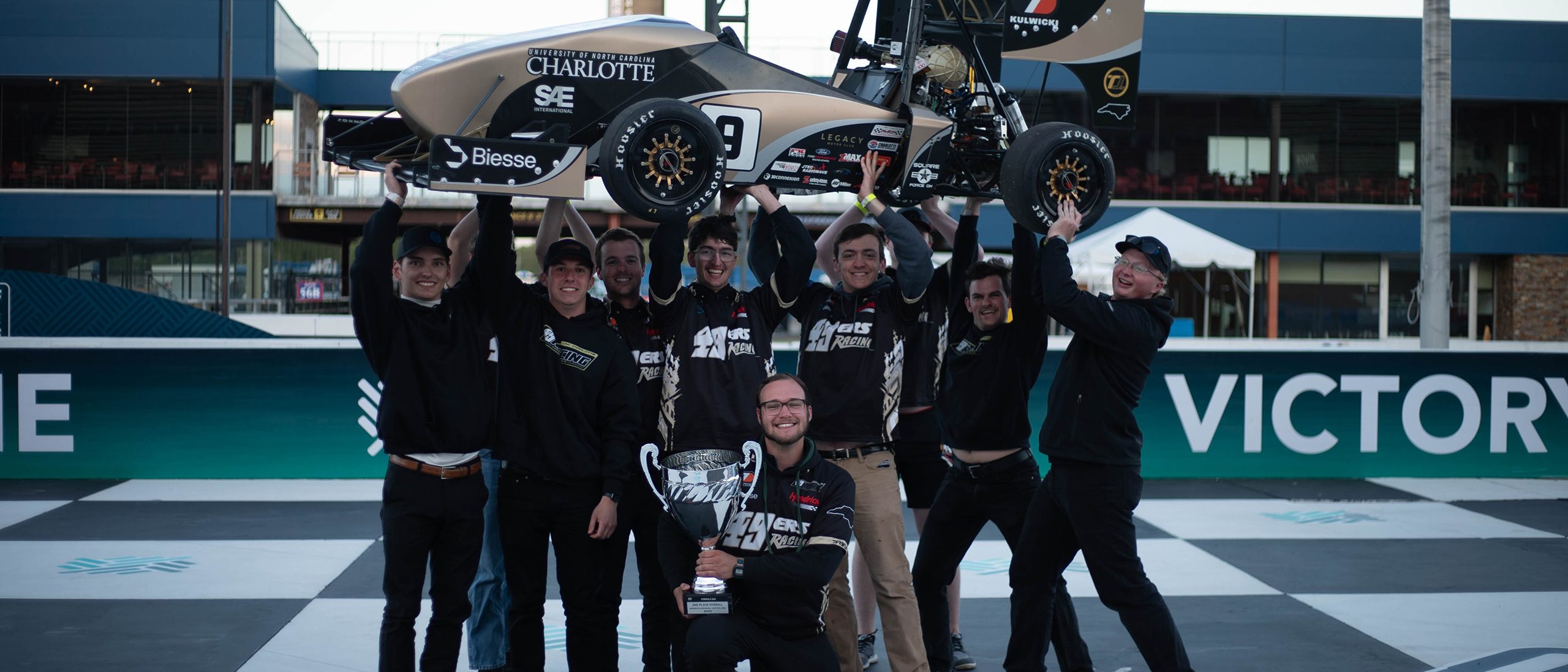 49ers Racing team members hoist race car in the air