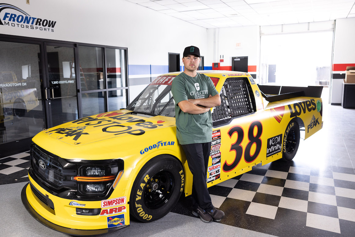 Layne Riggs standing with his No. 28 race truck